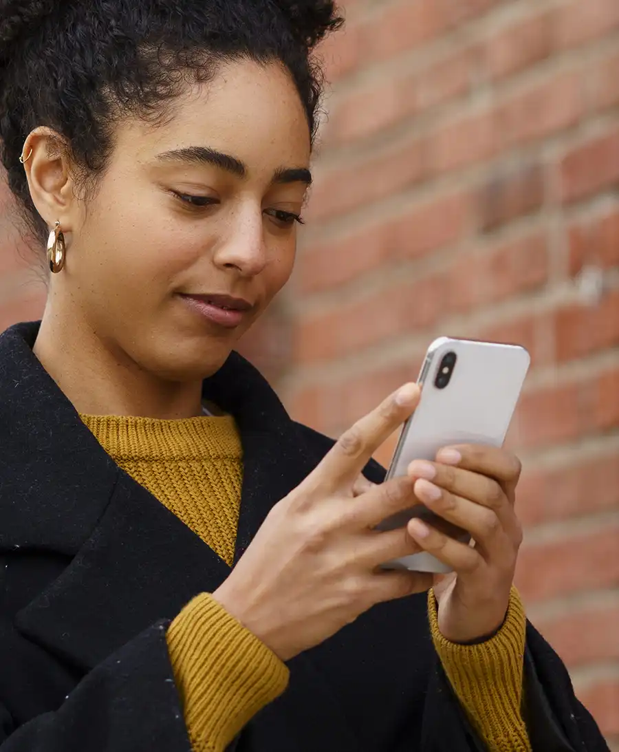 Woman on smartphone outside with brick building behind her